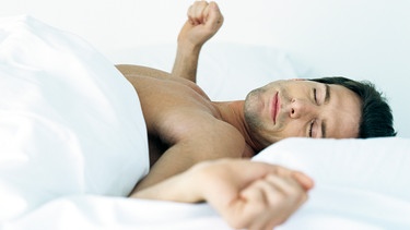 Bei Rückenschmerzen progressive Muskelentspannung (im Bild: Mann mit geballten Fäusten, aber entspannt im Bett) | Bild: colourbox.com