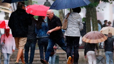 Fußgänger im Regen laufen durcheinander. Warum stoßen Fußgänger nicht fortwährend zusammen? Und warum stoßen sie dauernd zusammen? Beide Fragen wurden erforscht - und beide Studien jeweils mit einem Ig-Nobelpreis 2021 ausgezeichnet. | Bild: dpa-Bildfunk/Bob Edme