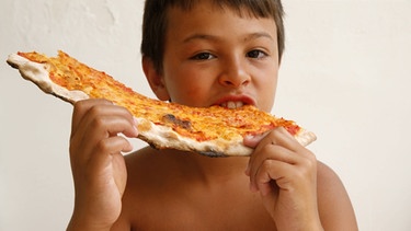 Junge isst eine Pizza. Wer in Italien eine echte italienische Pizza isst, kann Krankheit und Tod vorbeugen. Für diese obskure Erkenntnis gab es den Ig-Nobelpreis 2019 für Medizin. | Bild: picture alliance / Godong