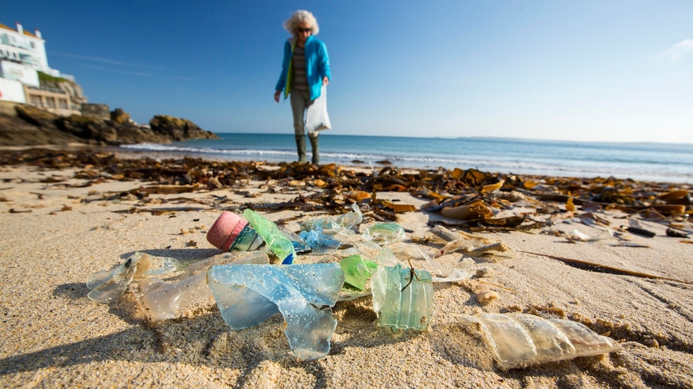 Eine Frau sammelt Plastikmüll am Strand von St. Ives, Cornwall, Großbritannien. | Bild: picture alliance / Global Warming Images | Ashley Cooper