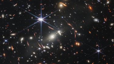 Das von der US-amerikanischen Weltraumbehörde NASA zur Verfügung gestellte Bild zeigt den Galaxienhaufen SMACS 0723, aufgenommen mit dem James-Webb-Weltraumteleskop. Das Bild, genannt «Webb's First Deep Field», das als erstes dieses Teleskops veröffentlicht wurde, deckt einen Himmelsausschnitt ab, der etwa so groß ist wie ein Sandkorn, das jemand auf dem Boden in der Hand hält - und enthüllt Tausende von Galaxien in einem winzigen Ausschnitt des riesigen Universums. Webbs scharfe Nahinfrarot-Aufnahme, die durch die Nahinfrarotkamera (NIRCam) von Webb aufgenommen wurde, brachte schwache Strukturen in extrem weit entfernten Galaxien zum Vorschein und bietet den bisher detailliertesten Blick auf das frühe Universum. Das Ergebnis ist ein Komposit aus Bildern verschiedener Wellenlängen, die insgesamt 12,5 Stunden lang aufgenommen wurden - damit wurden bei Infrarot-Wellenlängen Tiefen erreicht, die über die tiefsten Felder des Hubble-Weltraumteleskops hinausgehen, die Wochen benötigten. Das Bild zeigt den Galaxienhaufen SMACS 0723, wie er vor 4,6 Milliarden Jahren erschien. | Bild:  Space Telescope Science Institut/NASA/ESA/CSA/dpa +++ dpa-Bildfunk +++ 