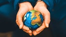 Hände halten eine Weltkugel in der Hand. Wie können wir unseren Planeten retten? | Bild: picture-alliance/dpa