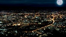 Eine Stadt in der Nacht: Das künstliche Licht strahlt von den Häusern und Wohnungen in den Nachthimmel hinaus. Künstliches Licht stört viele nachtaktive Tiere und trägt deshalb zum Artensterben bei. | Bild: colourbox.com