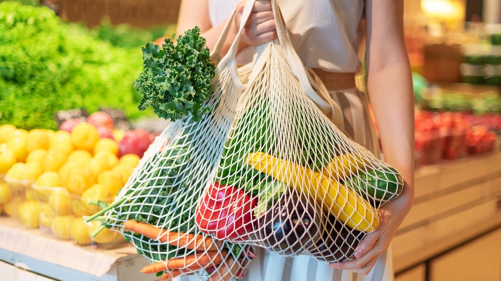 Eine Frau steht mit einem Einkaufsnetz in einer Gemüseabteilung. Durch eure Ernährung könnt ihr den Artenschutz und die Biodiversität unterstützen. | Bild: colourbox.com