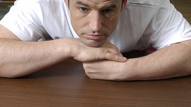 Depressionen: Depressiver Mann stützt Kopf mit Kinn auf seine Hände | Bild: picture-alliance/dpa