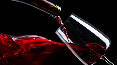 Mit einer Flasche wird ein Glas Rotwein eingegossen. Ein Glas Rotwein am Abend gilt als gesund, ist aber schon zu viel. | Bild: colourbox.com