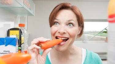 Die richtigen Essenstipps bei Stress - hier im Video. Im Bild: Frau isst eine Karotte aus dem Kühlschrank. | Bild: picture alliance / imageBROKER | uwe umstätter