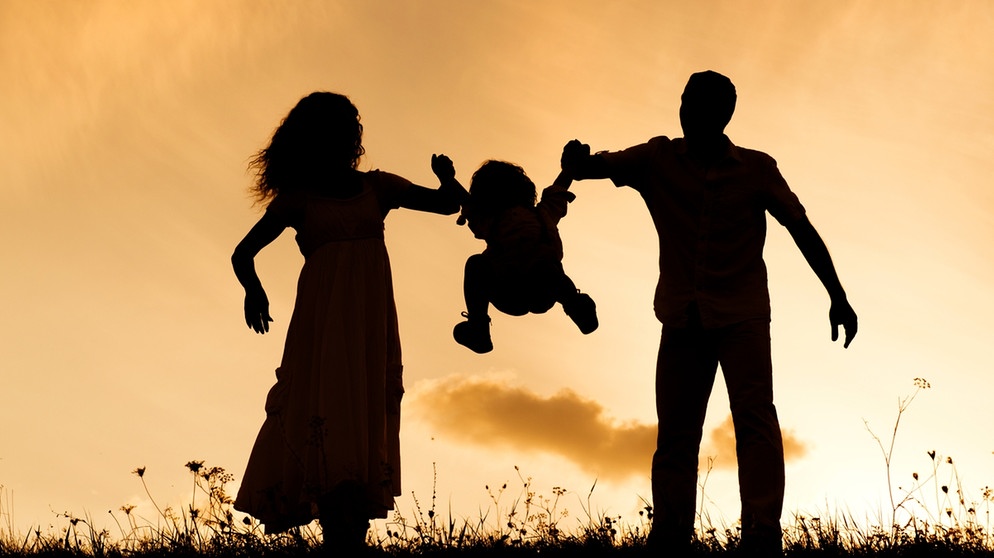 Eine Frau und ein Mann heben ein kleines Kind in die Luft. | Bild: colourbox.com
