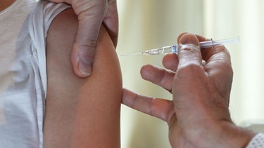Ein Arzt impft eine Patientin gegen Grippe. | Bild: picture alliance/dpa/dpa-Zentralbild | Jens Kalaene