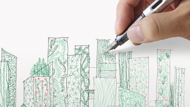 Die Hand eines Stadtplaners entwirft auf einem Blatt Papier eine Stadt mit "grüner Infrastruktur". Nachhaltiges Bauen wird gegen Hitze und Starkregen in Städten immer wichtiger.  | Bild: colourbox.com