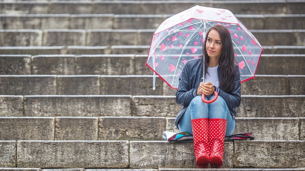 Frau schützt sich mit Regenschirm vor Regen. | Bild: colourbox.com
