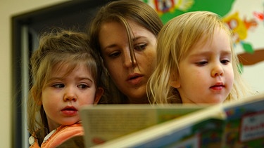 Erzieherin beim Vorlesen mit zwei Kindergartenkindern  | Bild: BR