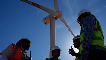 Ingenieure neben einer Windturbine im Gespräch in der Lekela Windenergie Station, in der Nähe von Ras Ghareb, 300 Kilometer von Kairo entfernt | Bild: picture-alliance/ASSOCIATED PRESS/Amr Nabil