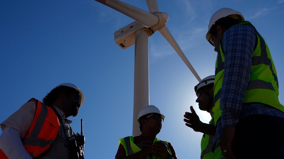 Ingenieure neben einer Windturbine im Gespräch in der Lekela Windenergie Station, in der Nähe von Ras Ghareb, 300 Kilometer von Kairo entfernt | Bild: picture-alliance/ASSOCIATED PRESS/Amr Nabil