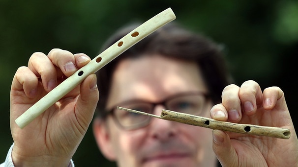 Der Musikarchäologe Arnd Adje Both zeigt den Nachbau einer 38000 Jahre alten Flöte aus Geierflügelknochen (l.) und eine Flöte aus Mammutelfenbein. | Bild: picture alliance / dpa | Wolfgang Kumm