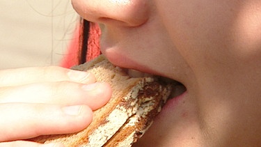 Eine junge Frau beißt in ein Brot | Bild: BR