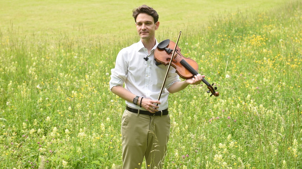 Stanko Madic, erster Konzertmeister des Müncher Rundfunkorchesters, steht mit seiner Geige in einer Blumenwiese. | Bild: Bayerischer Rundfunk 2021