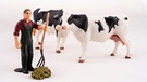 Miniaturfiguren: Ein Bauer mit Mistgabel und zwei Milchkühen bei einem Kuhfladen. | Bild: stock.adobe.com/Tetiana Liubarska