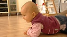 Ein Baby krabbelt am Boden | Bild: BR