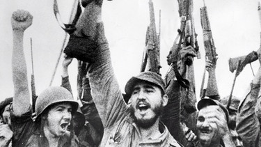 Fidel Castro, langjähriger Staatspräsident Kubas, hier triumphierend als treibende Kraft der Kubanischen Revolutionsbewegung. Das Foto zeigt wie Fidel Castro und seine Kämpfer im Mai 1957 in der Sierra Maestra "wir leben noch"demonstrieren, nachdem die kubanische Regierung mitgeteilt hatte, dass die Rebellen längst aufgerieben und vernichtet seien.  | Bild: picture-alliance/dpa