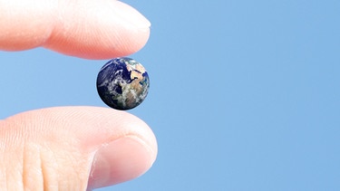 Eine Person hält ein kleines Modell der Erde zwischen den Fingern | Bild: colourbox.com