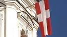 Der "Zachäus", eine rotweiße Fahne hängt am Raistinger Kirchturm | Bild: BR