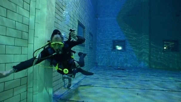 Ein Taucher schwebt in einem Schwimmbecken  unter Wasser  | Bild: BR