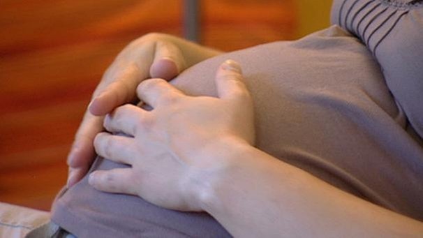 Eine Schwangere legt ihre Hände auf ihren Bauch | Bild: BR