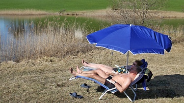 Leute unterm Sonnenschirm am See | Bild: picture-alliance/dpa