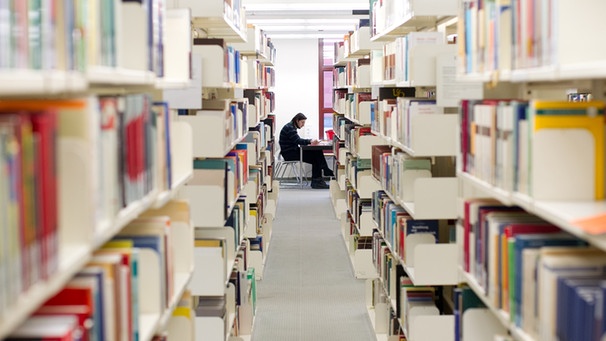 Blick zwischen den Regalen in einer Unibibliothek | Bild: picture-alliance/dpa
