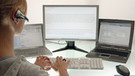 Frau tippt auf Tastatur, mehrere Bildschirme im Hintergrund | Bild: picture-alliance/dpa