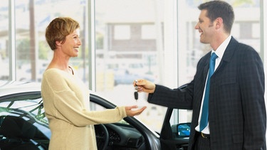 Autoverkäufer übergibt einer Kundin den Autoschlüssel | Bild: Image Source