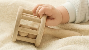 Baby greift im Kinderbett nach einer Rassel | Bild: colourbox.com