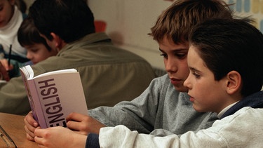 Zwei Jungen auf der Schulbank lernen gemeinsam Englisch | Bild: Getty Images