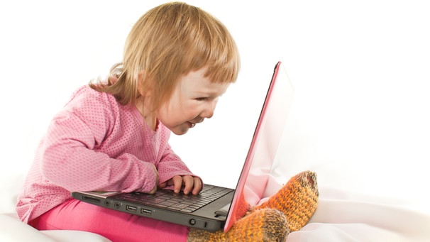 rosarot gekleidetes kleines Mädchen sitzt vor einem Laptop auf dem Bett | Bild: colourbox.com