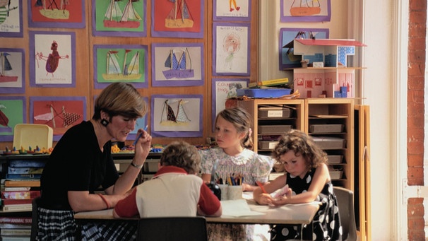 Zwei Schülerinnen und ein Schüler sitzen mit ihrer Lehrerin in einer Lerngruppe zusammen | Bild: Getty Images