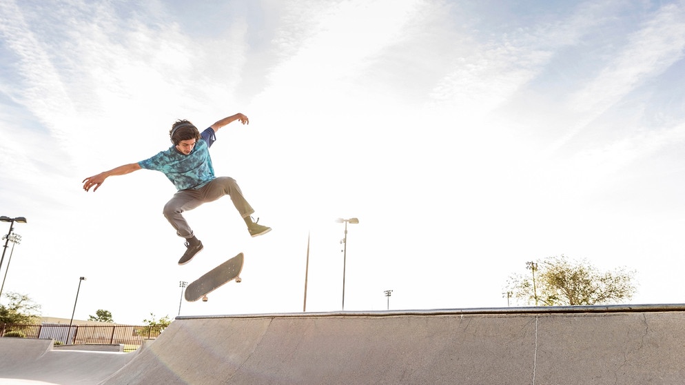 Junger Mann führt in der Luft einen Trick beim Skaten aus. | Bild: picture alliance / Bildagentur-online/Blend Images | Blend