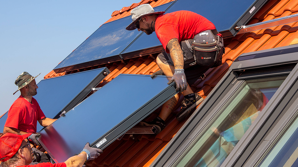 Handwerker installieren eine Solaranlage auf einem Dach | Bild: imago images/U. J. Alexander