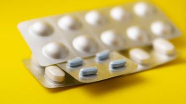Verschiedene Tabletten liegen auf einem gelben Hintergrund. Viele Menschen sind von Tabletten, Cannabis oder Alkohol abhängig. | Bild: picture-alliance/dpa