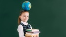 Ein Mädchen mit einer Weltkugel auf dem Kopf und Büchern in der Hand. Beim Lernen und Üben von Fremdsprachen kommt es auf Grammatik und Vokabeln an.  | Bild: colourbox.com
