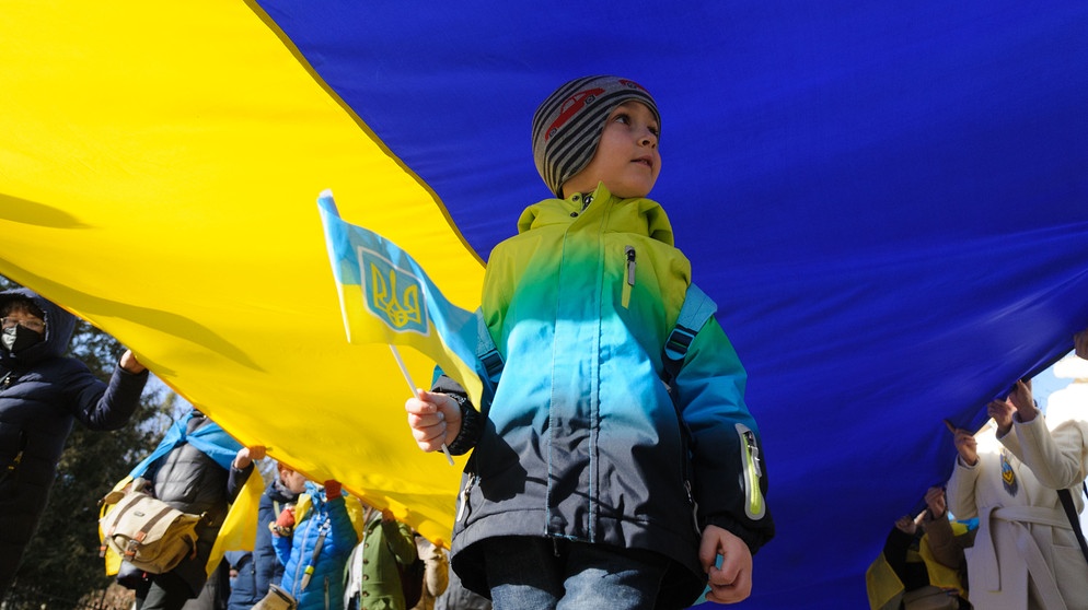 Ein kleiner Junge mit der ukrainischen Flagge während eines Protestzugs an der ukrainisch-russischen Grenze am 19. Februar 2022 | Bild: picture alliance / ZUMAPRESS.com | Mykola Tys