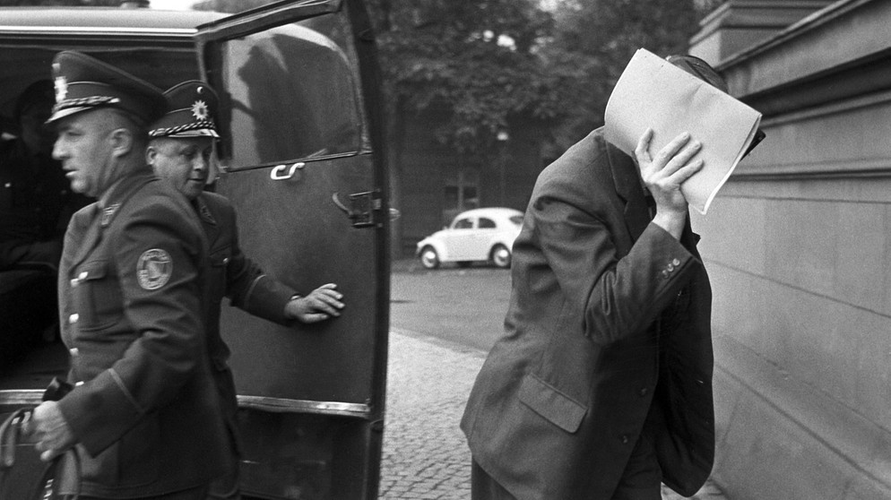 Der Hauptangeklagte im Doppelagentenprozess Heinz Felfe verdeckt auf dem Weg ins Gerichtsgebäude am 08.07.1963 mit einem Aktendeckel sein Gesicht. | Bild: picture alliance / Fritz Fischer | Fritz Fischer