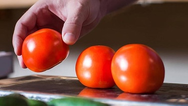 Eine Person legt in einem Supermarkt Tomaten auf die Waage. | Bild: imago-images/Nomad Soul/Panthermedia