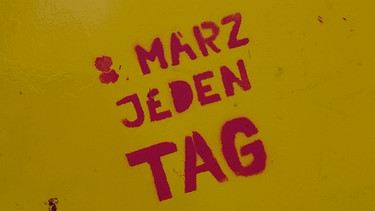 Pinke Graffittischrift "8. März jeden Tag" auf gelbem Grund | Bild: picture alliance / Pacific Press | Michael Debets