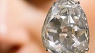 Hochkarätiger geschliffener Diamant an einem weißen Band. Diamanten sind Edelsteine mit eine sehr hohen Lichtbrechung und einem funkelnden Glanz, der durch einen sorgfältigen Schliff noch zusätzlich verstärkt wird.  | Bild: BR
