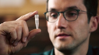 Prof. Reinhard Heckel betrachtet ein kleines Reagenzfläschen mit DNA-Material.  | Bild: BR/Gut zu wissen