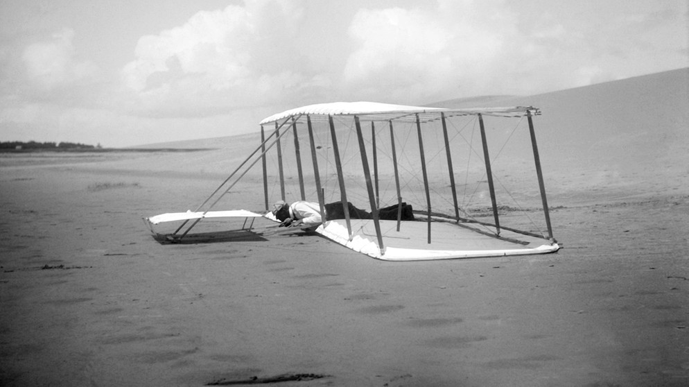 Wilbur Wright nach einer Landung 1901. Die Brüder Orville und Wilbur Wright verband der gemeinsame Traum vom Fliegen. Anfang des 20. Jahrhunderts versuchten sie ihn wahr zu machen - und es gelang! Wir erklären euch mehr über die beiden Pioniere des Motorflugs.  | Bild: picture alliance / Glasshouse Images | Circa Images