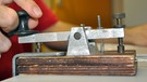 Hand an Morseapparat - Samuel Morse hat das Morsen erfunden und war Wegbereiter der Telegrafie | Bild: picture-alliance/dpa