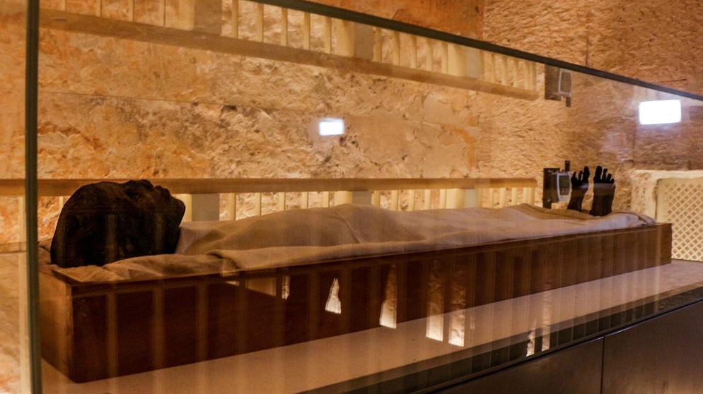 Zu sehen ist Tutanchamuns Mumie in einer Glaskammer. Der junge Pharao Tutanchamun ist die Ikone des Alten Ägypten. Die Entdeckung seiner Grabkammer, seiner Mumie mit der Goldmaske und den wertvollen Grabschätzen durch den Archäologen Howard Carter machten ihn weltberühmt. | Bild: picture alliance/dpa/Eslam Kotb
