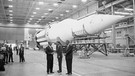 Wernher von Braun (von links), der US-amerikanische Praesidenten John F. Kennedy und der Vizepraesidenten Lyndon B. Johnson, unterhalten sich in dem Montagewerk einer Saturn-Rakete in Huntsville. | Bild: dapd